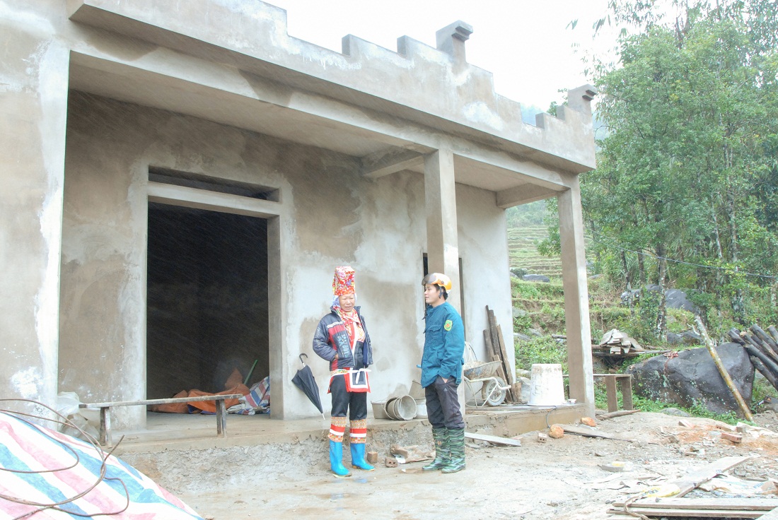 Anh Tằng A Sám, Bí thư Chi bộ, Trưởng bản Khe Mọi, xã Đồng Văn (bên phải) nắm tình hình hộ nghèo của bản được hỗ trợ xây nhà.