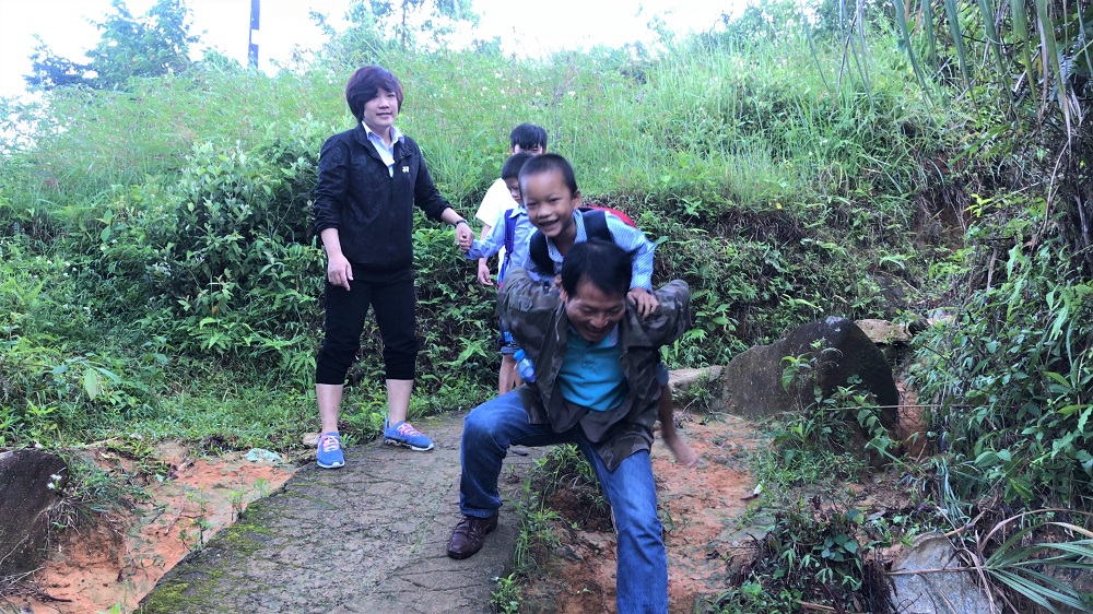 Thầy giáo Loan Thanh Tào, ở điểm trường Sông Moóc B, trường Tiểu học Đồng Văn, xã Đồng Văn, huyện Bình Liêu cõng học sinh đi qua đoạn đường khó.