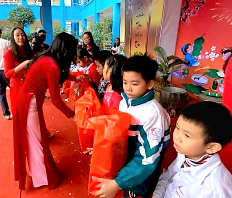 Trưởng tiểu học Quang Trung tặng quà cho các học sinh nghèo của trường từ Phong trào ủng hộ bạn nghèo đón tết của nhà trường.