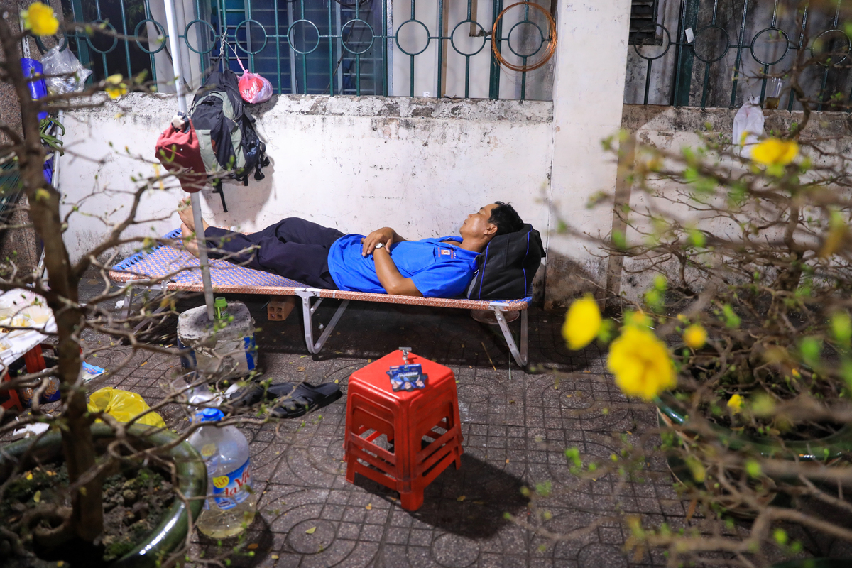 Một nhà vườn ngủ tạm trên chiếc ghế bố để canh mai trên đường Bến Bình Đông về đêm.