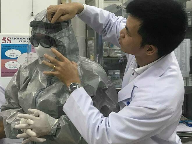 Thứ trưởng Nguyễn Trường Sơn mặc đồ bảo hộ vào phòng cách ly thăm 2 bệnh nhân đang điều trị tại Bệnh viện Chợ Rẫy tối 23/1. Ảnh: Đ.H