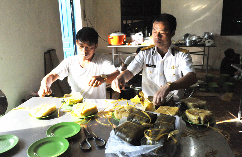 Thiếu tá Triệu Văn Tuyến (phải) - rể của Quảng Ninh đang cắt bánh chưng để đãi khách.