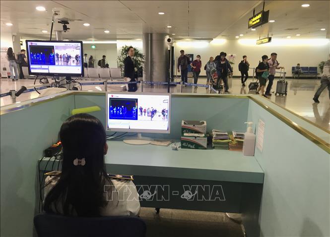 Nhân viên sân bay Tân Sơn Nhất kiểm tra màn hình hiển thị máy quét thân nhiệt đối với hành khách quốc tế đến Việt Nam. Ảnh: Đinh Hằng/TTXVN