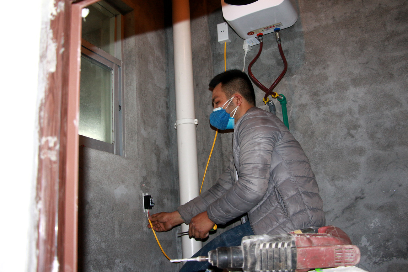 Công nhân đang lắp đặt các thiết bị điện tại các phòng ở, phục vụ người dân cách ly.