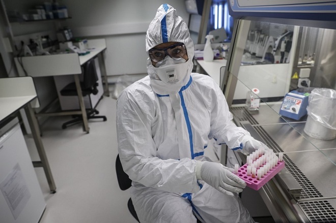 Nhà khoa học thu thập mẫu bệnh phẩm của người bệnh. Ảnh: AFP