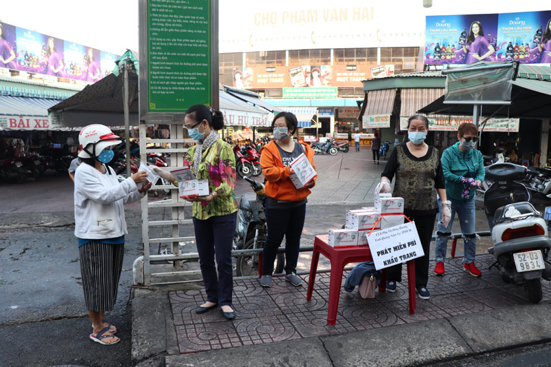Các thành viên CLB Phụ nữ tỉnh Quảng Ninh tại TP Hồ Chí Minh phát miễn phí khẩu trang cho người đi đường tại cổng chợ Phạm Văn Hai, phường 3, quận Tân Bình (TP Hồ Chí Minh).