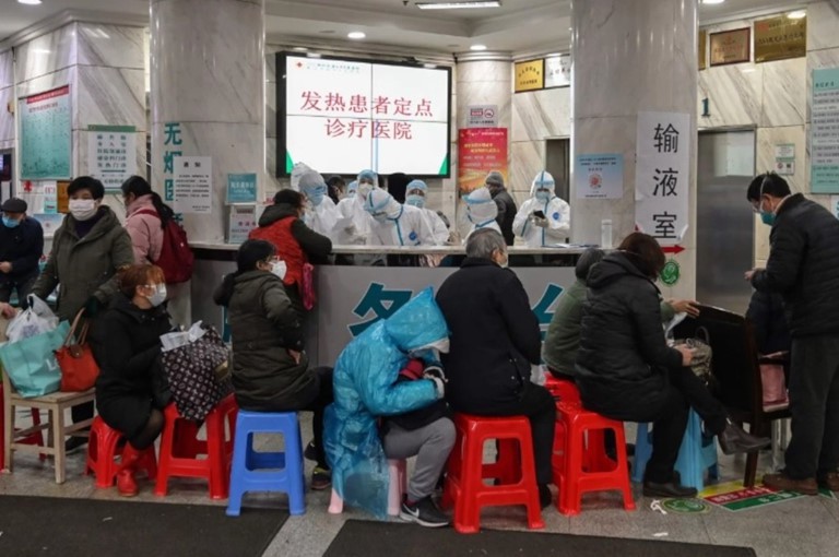 Bệnh nhân ngồi xếp hàng chờ trước một bệnh viện quá tải ở Vũ Hán. (Ảnh: Reuters).