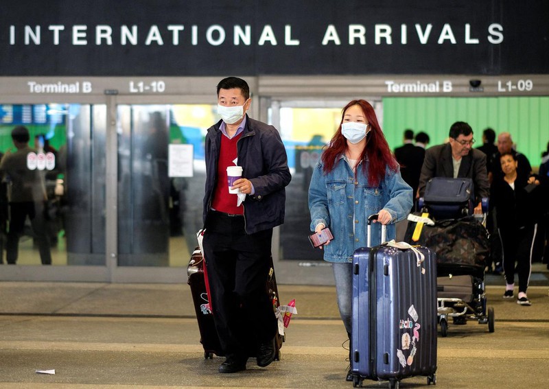 Hành khách đeo khẩu trang để phòng lây nhiễm virus corona khi đến sân bay quốc tế ở Los Angeles, Mỹ. Ảnh: Reuters.