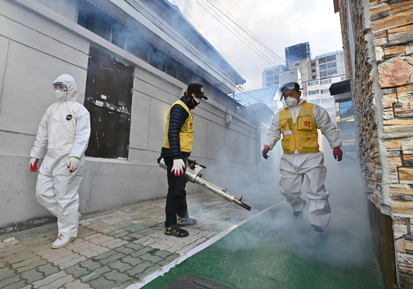 Nhân viên y tế khử trùng tại một khu dân cư gần nhà thờ giáo phái Tân Thiên Địa ở thành phố Daegu ngày 27-2 - Ảnh: AFP