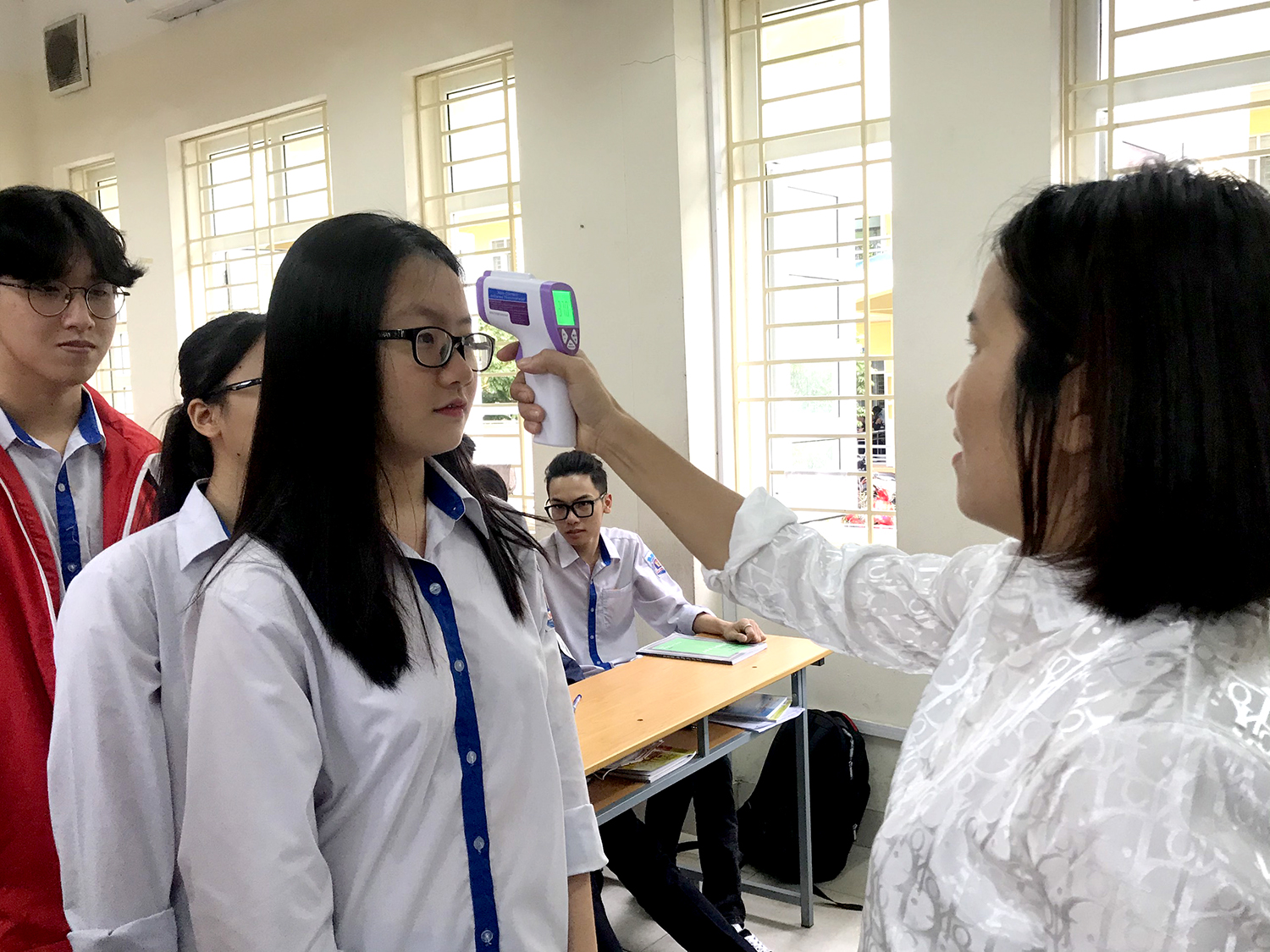 Trường THPT Hòn Gai (TP Hạ Long) kiểm tra thân nhiệt lần 2 cho học sinh trong lớp học sau khi đã kiểm tra ở cổng trường. 