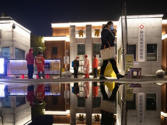 Công nhân đeo khẩu trang trước một bệnh viện dã chiến đã đóng cửa ở TP Vũ Hán, tỉnh Hồ Bắc (Trung Quốc) sau khi những bệnh nhân cuối cùng đã xuất viện. Ảnh: REUTERS