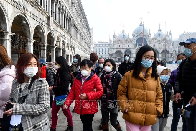 Khách du lịch đeo khẩu trang đề phòng lây nhiễm COVID-19 tại Venice, Italy ngày 24/2/2020. Ảnh: AFP/TTXVN