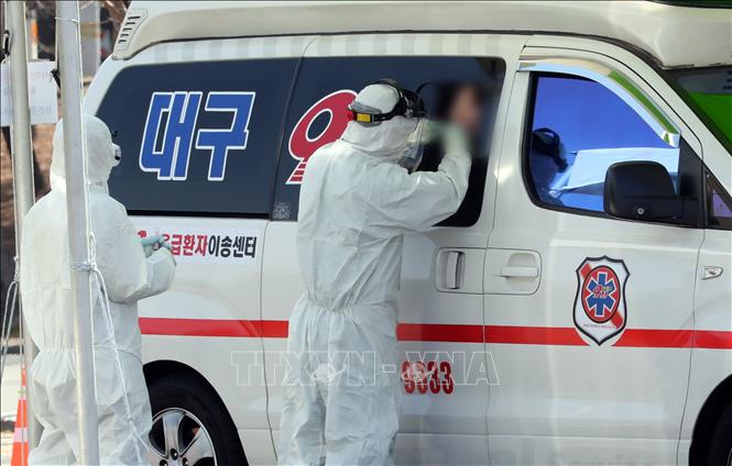 Nhân viên y tế lấy mẫu bệnh phẩm từ một trường hợp nghi nhiễm COVID-19 trên xe cứu thương tại thành phố Daegu, Hàn Quốc ngày 6/3/2020. Ảnh: Yonhap/TTXVN