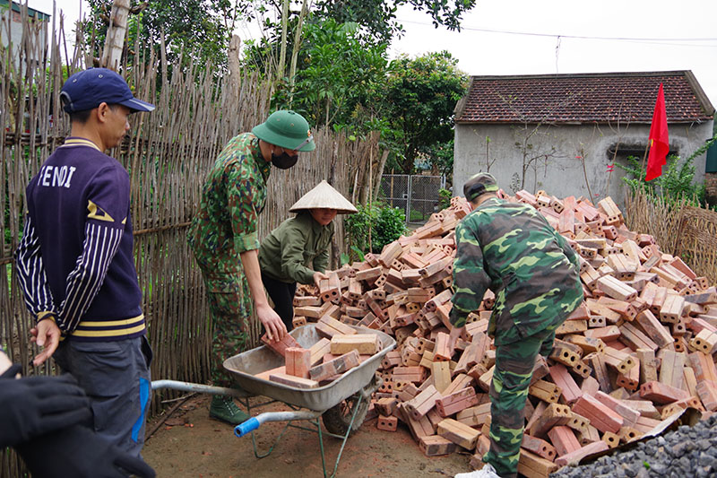 Các lực lượng tham gia vận chuyển vật liệu xây dựng nhà cho hộ nghèo.