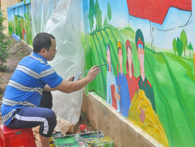 Các thầy cô trường học Tiểu học xã Quảng Lâm vẽ tranh trên tường rào của trường tạo cảnh quan sạch- đẹp cho xã. Ảnh: Thu Nguyệt