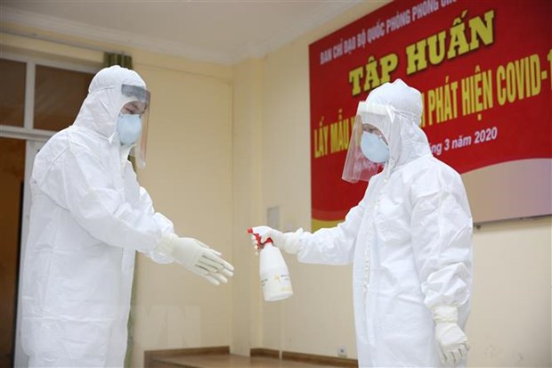 Nhân viên y yế khử khuẩn sau khi lấy mẫu bệnh phẩm của người nghi nhiễm SARS-CoV-2. (Ảnh: Dương Giang/TTXVN)