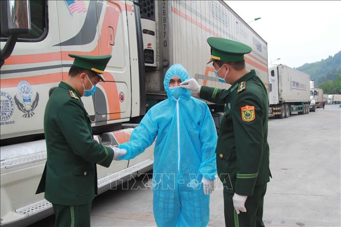 Lực lượng biên phòng Tân Thanh (Lạng Sơn) chỉnh trang quần áo bảo hộ cho lái xe chuẩn bị thông quan hàng hóa tại cửa khẩu. Ảnh: Quang Duy/TTXVN
