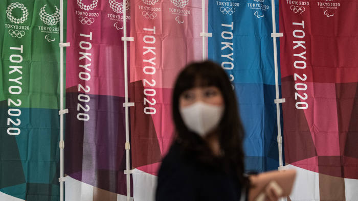 Người dân đeo khẩu trang đi qu những banner Thế vận hội Tokyo 2020 tại Thủ đô Tokyo, Nhật Bản. Ảnh: Reuters