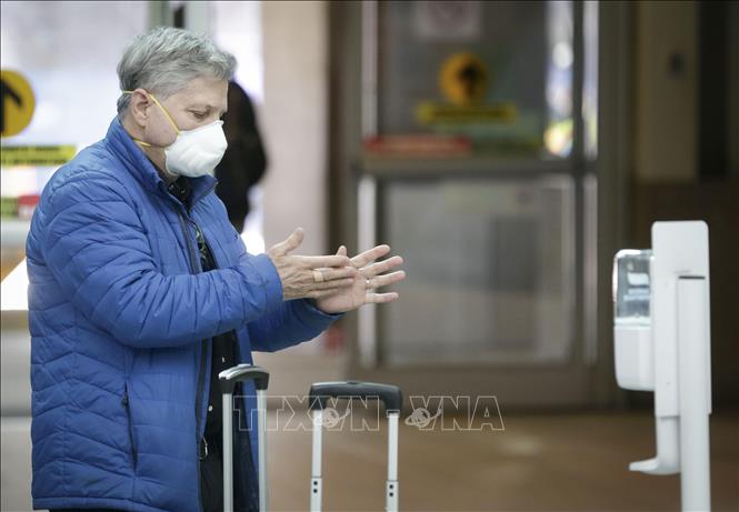 Hành khách sử dụng nước sát khuẩn để phòng tránh lây nhiễm COVID-19 tại sân bay quốc tế Vancouver ở Richmond, Canada, ngày 16/3/2020. Ảnh: THX/TTXVN