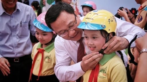 Ông Khuất Việt Hùng, Phó Chủ tịch Uỷ ban ATGT Quốc gia trao mũ bảo hiểm cho các cháu học sinh lớp 1. Ảnh: VGP.