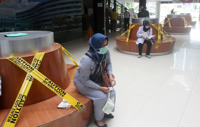 Du khách ngồi theo chỗ được chỉ định tại ghế chờ trong bệnh viện Padang, Indonesia. Ảnh: Reuters