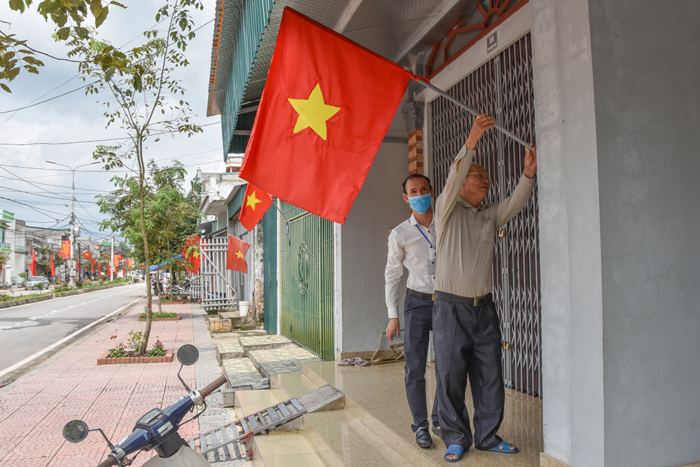 Người dân khu phố Minh Khai, thị trấn Đầm Hà, treo cờ tổ quốc chào mừng Đại hội Đảng bộ thị trấn dự kiến diễn ra đầu tháng 4/2020. Lan Anh