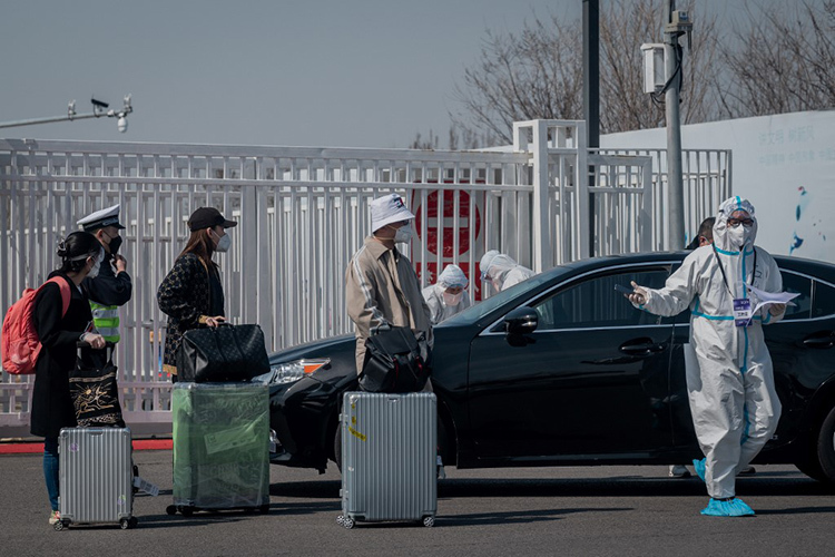 Nhân viên y tế hướng dẫn hành khách về từ nước ngoài tại trung tâm triển lãm quốc tế Tân Hoa gần sân bay Bắc Kinh hôm 16/3. Ảnh: AFP