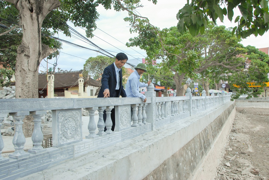 Cán bộ MTTQ phường Phong Cốc, TX Quảng Yên (trái) giám sát thi công vỉa hè, bờ hồ khu 6 của phường.