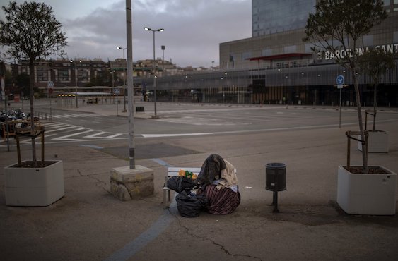 Một người đàn ông đến từ vùng Hạ Sahara, châu Phi co mình tại một bãi đỗ xe bên ngoài ga tàu ở Barcelona, Tây Ban Nha. Ảnh AP
