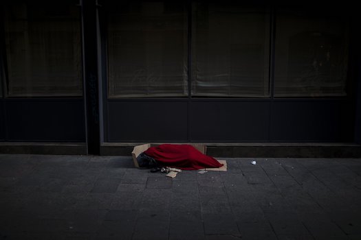 Một người đàn ông phủ chăn ngủ trên một con đường vắng ở Barcelona, Tây Ban Nha. Ảnh AP