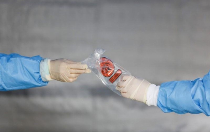 Hai nhân viên y tế Mỹ trao nhau mẫu xét nghiệm SARS-CoV-2 của một bệnh nhân. Ảnh: Reuters