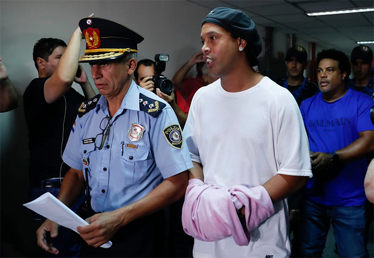 Ronaldinho được che còng tay khi cảnh sát áp giải anh vào nhà tù ở Assuncion, Paraguay hôm 5/3. Ảnh: AP.
