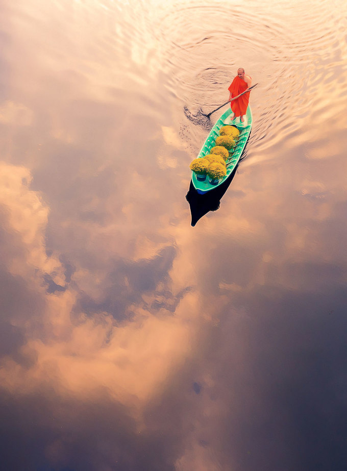 Nhiếp ảnh gia Nguyễn Tấn Tuấn chụp bức ảnh “Thuyền hoa” (Boat Carrying Flowers) bằng DJI Mavic 2 Pro, ghi lại cảnh nhà sư chèo thuyền chở những chậu cúc mâm xôi về chưng Tết ở tỉnh Đồng Tháp. “Mây in bóng trên dòng nước tạo cảm giác như con thuyền đang trôi trên mây”, anh Tuấn cho biết.  Trung tuần tháng 3/2020, BTC của SkyPixel - cuộc thi chụp ảnh trên không quốc tế lần thứ 5 (2014-2019) công bố 56 tác phẩm ảnh, video đạt giải ở các hạng mục gồm du lịch, thành phố, kiến trúc, chân dung, thiên nhiên và thể thao với tổng trị giá giải thưởng hơn 117.000 USD. Từ 2014 đến nay, cuộc thi thu hút 18 triệu nhiếp ảnh gia chuyên chụp trên không đến từ 140 quốc gia và vùng lãnh thổ tham dự.