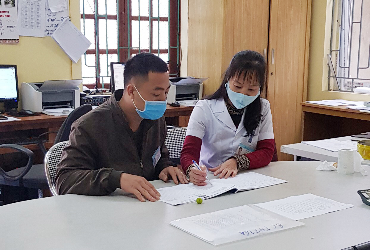 Anh Dương Đình Quang, cán bộ dân số xã Điền Xá, huyện Tiên Yên trao đổi công việc với cán bộ y tế trạm y tế xã Điền Xá.