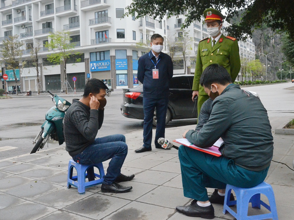 Lực lượng chức năng phường Hồng Hải, TP Hạ Long, lập biên bản xử phạt người ra đường không đeo khẩu trang. 