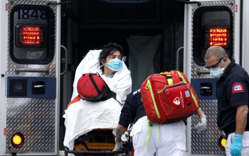 Một bệnh nhân mắc Covid-19 tại New York đang được đưa lên xe cứu thương để nhập viện. Ảnh: Reuters
