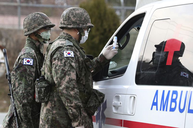 Binh sĩ Hàn Quốc đeo khẩu trang kiểm tra thân nhiệt tài xế tại Daegu. Ảnh: AP