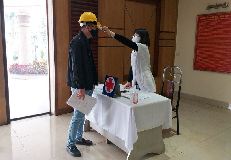 Cán bộ Trung tâm Y tế, Công ty CP Than Cọc Sáu – Vinamcomin kiểm tra thân nhiệt cán bộ, nhân viên ra, vào trụ sở làm việc. Ảnh: Quang Minh chụp ngày 14/4