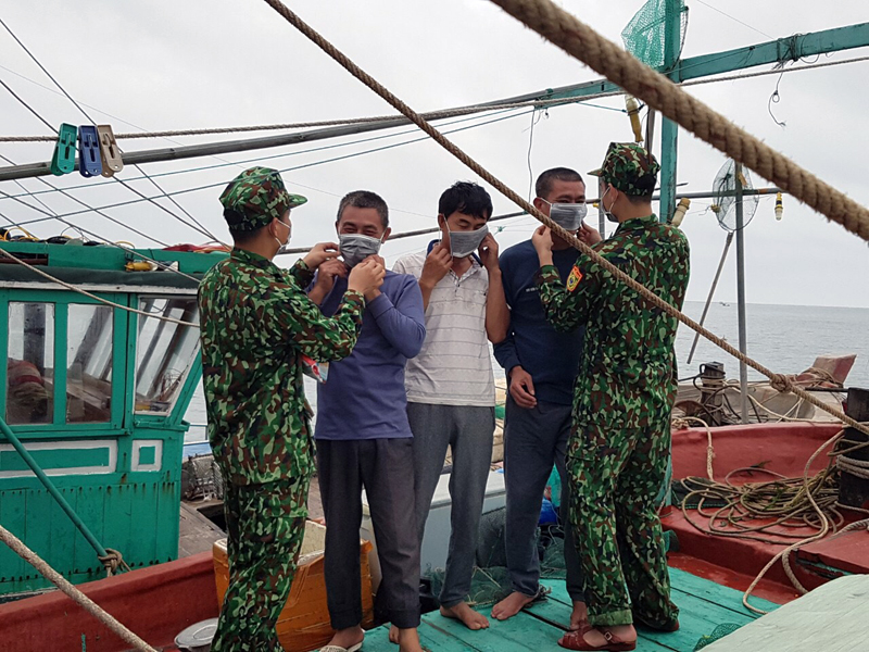 Cán bộ Đồn Biên phòng Trà Cổ hướng dẫn ngư dân trên địa bàn cách đeo khẩu trang y tế để phòng dịch.