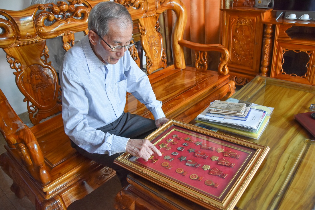 Cựu chiến binh Bùi Duy Thinh bên những kỷ vật chiến tranh, bao gồm 2 cuốn nhật ký.