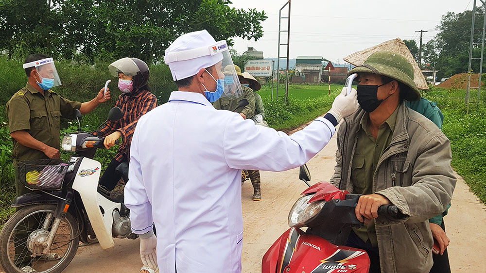 Lực lượng chức năng kiểm tra thân nhiệt tại chốt kiểm tra thôn Đồng Tâm, xã Dực Yên. Ảnh: Thái Cảnh