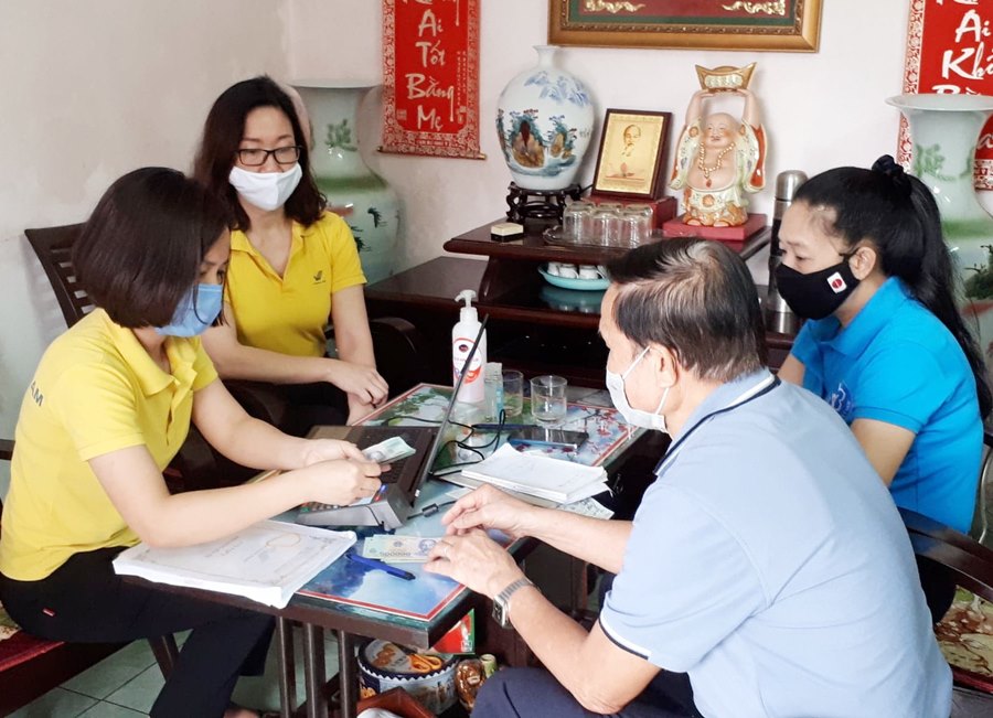 Cán bộ Bưu điện TP Hạ Long và BHXH tỉnh thực hiện thủ tục tri trả lương hưu cho ông Doàn Hải Yến ở phương Hà Tu (TP Hạ Long).