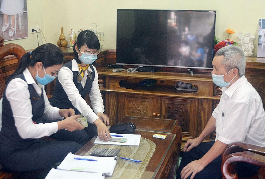 Nhân viên ngành Bưu điện thực hiện chi trả lương hưu tại nhà cho ông Đào Văn Gạo (khu 1, phường Hà Phong, TP Hạ Long).