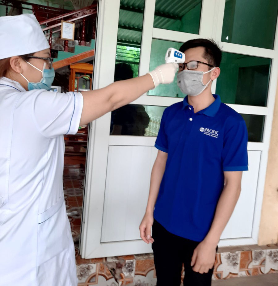 Cán bộ Trạm y tế xã Quảng An kiểm tra thân nhiệt anh Trần Văn Duy, thôn Hải An, người đang tự cách ly tại gia đình.