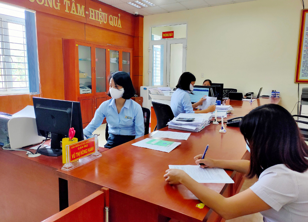Cán bộ BHXH huyện Bình Liêu hướng dẫn người dân làm thủ tục liên quan đến BHYT.
