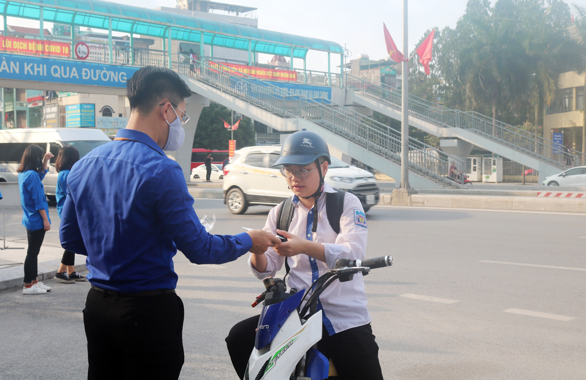 Đội thanh niên tình nguyện của Trường THPT Hòn Gai (TP Hạ Long) nhắc nhở học sinh mang khẩu trang trước khi vào trường.