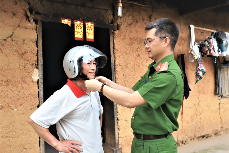 Đại úy La Minh Tâm, Trưởng Công an xã Đồng Tâm hướng dẫn người dân cách đội mũ bảo hiểm đúng quy định.