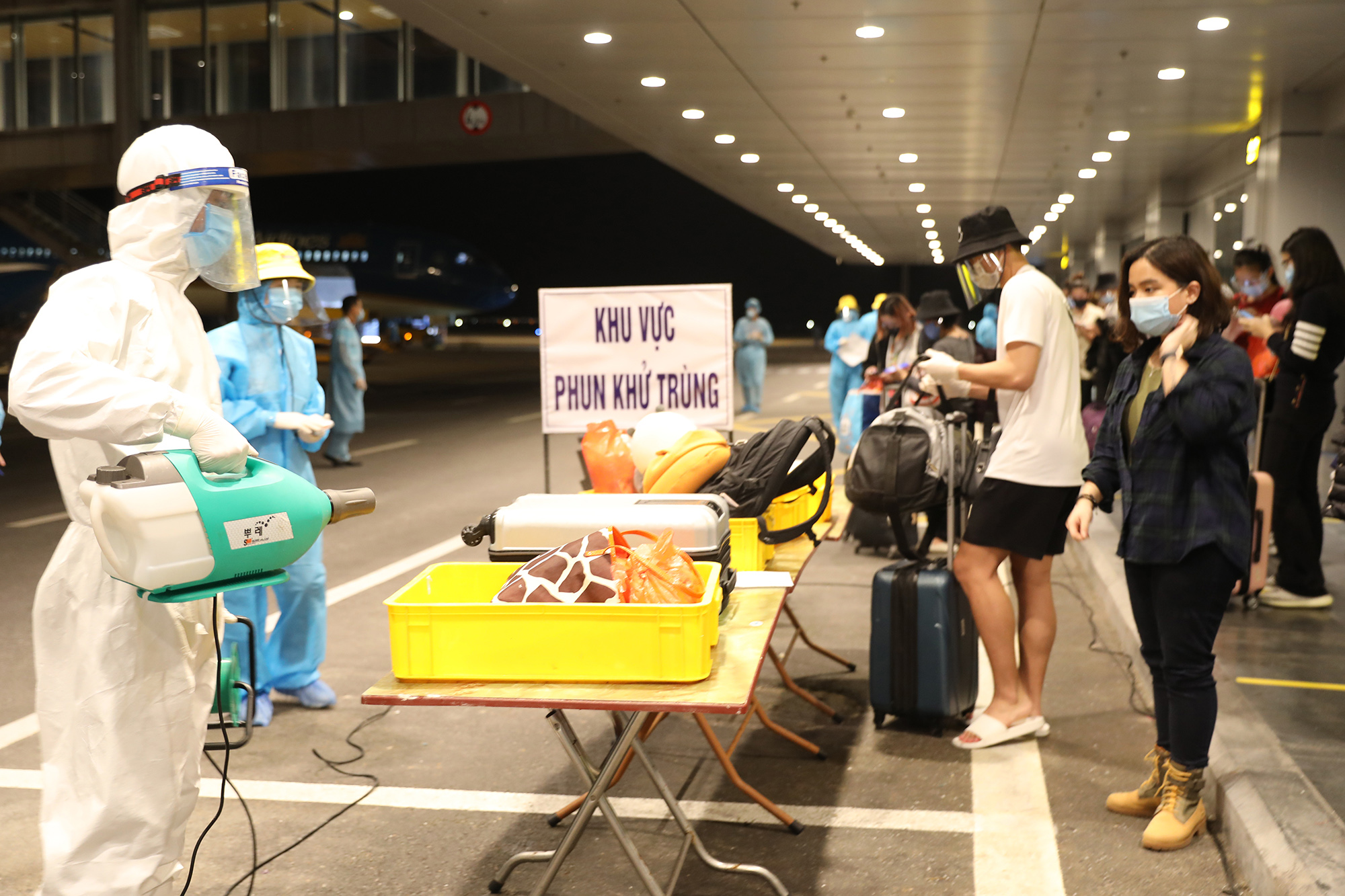 Hành lý xách tay của các hành khách trên chuyến bay từ Mỹ về được khử khuẩn trước khi làm thủ tục kiểm tra y tế