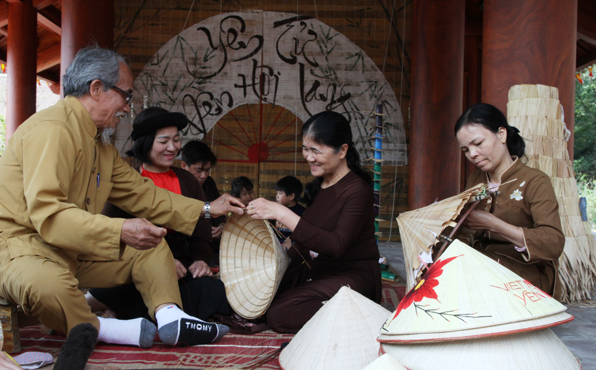 Artisan Pham Thanh Luong instructs tourists on how to make a conical hat