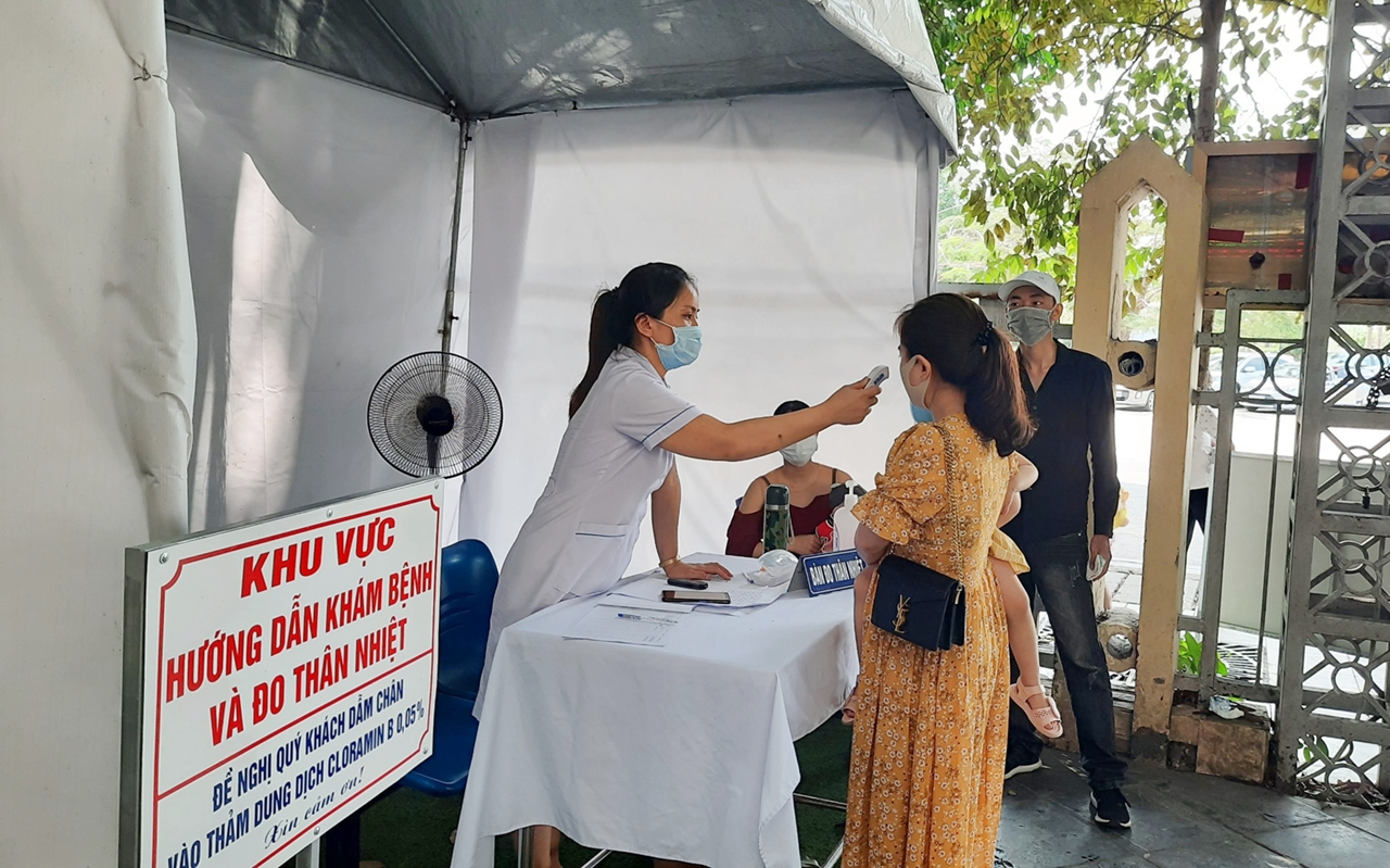 Trẻ đi tiêm chủng và người thân được đo thân nhiệt tại cổng Phòng tiêm chủng vắc-xin Safpo, Trung tâm Kiểm soát bệnh tật tỉnh.